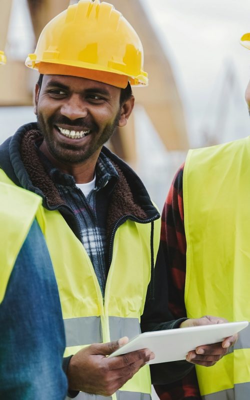 Multiracial engineer workers work at construction site using tablet computer - Focus on indian man