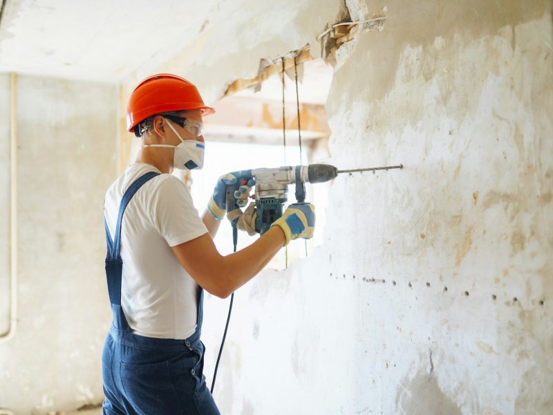 Repairer in boilersuit holding tools. Apartment repair and renovation concept. Building.